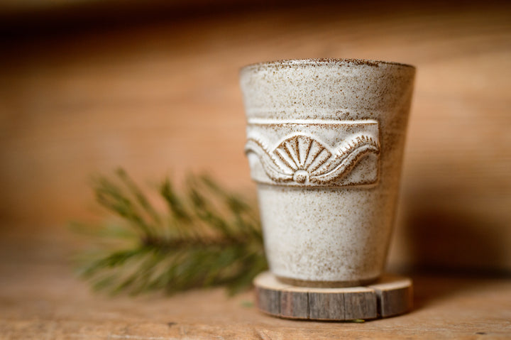 Keramisk mugg med dekor på träunderlägg