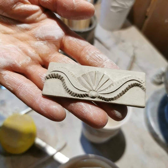 Keramikstämpel med Hälsingemagis mönster i en hand